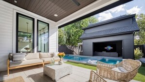 A modern outdoor living area with a pool, a sofa, and a television. - Amenities! Pool, Hot Tub, Theater, Outdoor kitchen (Austin)