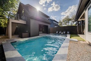 A modern house with a swimming pool, a covered deck, and a garage.