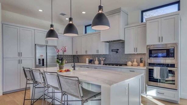 A modern kitchen with a large island, pendant lighting, and stainless steel appliances. - Amenities! Pool, Hot Tub, Theater, Outdoor kitchen (Austin)