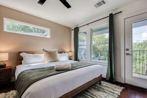 A bedroom with a large bed, a window, and a door.