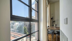 Ein Zimmer mit großem Fenster, Holzboden, Esstisch mit Stühlen und einer Tafel an der Wand.