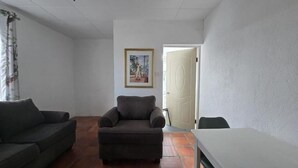 Una habitación con sofá, sillón y una mesa.