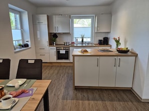 A modern kitchen with white cabinets, a central island, and a dining area with a table set for breakfast.