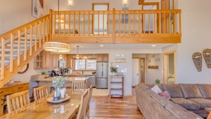 A spacious loft-style apartment with a wooden staircase, a dining area, a kitchen, and a living room. - Stylish and Modern Condo at Loon! Pool & Hot Tub (Lincoln)