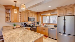 A kitchen with wooden cabinets, a stainless steel refrigerator, a microwave, and a coffee maker. - Stylish and Modern Condo at Loon! Pool & Hot Tub (Lincoln)