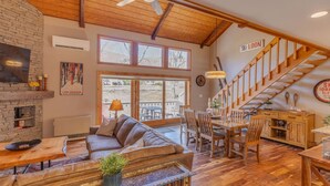 A cozy interior with a wooden staircase, a sofa, a dining table, and a fireplace. - Stylish and Modern Condo at Loon! Pool & Hot Tub (Lincoln)