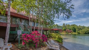 A lakeside hotel with a covered walkway, outdoor seating, and a sign warning of no lifeguard on duty. - Deer Park End Unit with Lake Access (Woodstock)