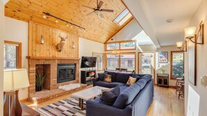A spacious living room with a fireplace, a large sofa, and a ceiling fan. - Deer Park End Unit with Lake Access (Woodstock)