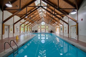 Ein Innenpool mit hoher Holzbalkendecke und großen Fenstern.