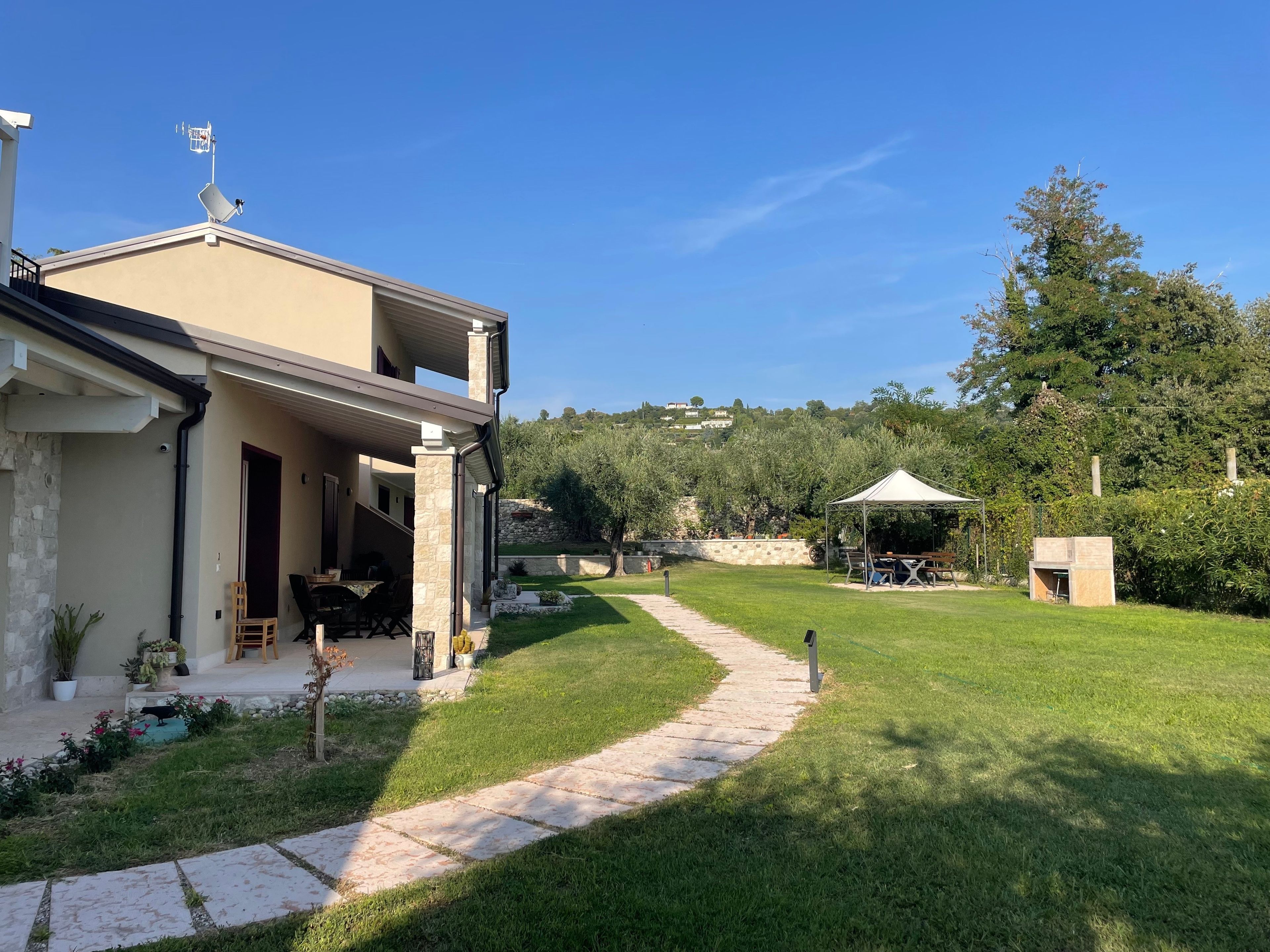 Une maison moderne à deux étages, dotée d’un patio couvert, d’un chemin en pierre et d’un jardin luxuriant.
