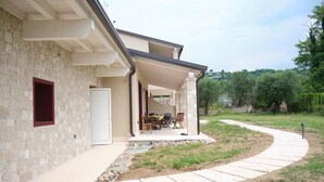Una casa con fachada de piedra, un porche cubierto y un camino pavimentado que conduce a la entrada.
