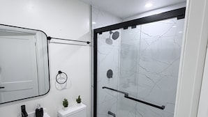 Une salle de bain moderne avec un lavabo blanc, des toilettes et une douche à parois de verre.