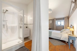 Een kamer met een douche, een bed, een nachtkastje en een raam.