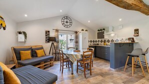 A cozy interior with a dining area, kitchen, and a loft-style bedroom with a sofa and a bed. - Guest Room 'Zépherine - Aux Charmes D’antan' with Shared Pool, Terrace & Wi-Fi (Sèvremont)
