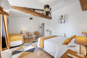 Una camera d'albergo con un letto, due sedie, una scrivania, una lampada e un quadro appeso al muro.
