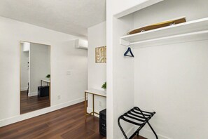Ein Zimmer mit Spiegel, Schreibtisch, Kleiderhaken und einem schwarzen Stuhl.
