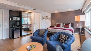 A modern hotel room with a bed, two armchairs, a small desk, and a mirror. - #RD1011 | Cyclinn Vila Olímpia (Vila Olímpia)