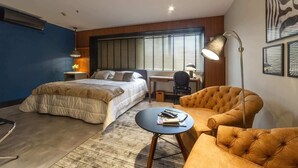 Een moderne slaapkamer met een bed, bureau, stoel en een klein tafeltje.