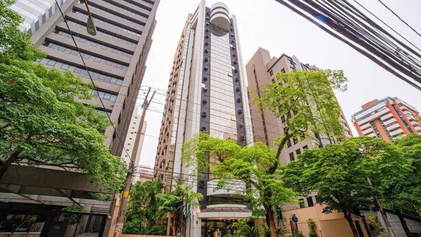 A high-rise building with a modern design, surrounded by trees and other buildings. - #TR410 | Cyclinn Faria Lima Itaim (Itaim Bibi)