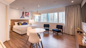 A modern hotel room with a bed, a dining table, two chairs, a desk, and a large window with curtains. - #RD809 | Cyclinn Vila Olímpia (Vila Olímpia)