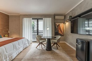 A modern hotel room with a bed, a round table with chairs, a TV, and a view of the outdoors. - #RB211 | Cyclinn Cidade Jardim - Itaim (Itaim Bibi)