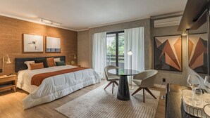 Quarto de hotel moderno com cama, uma mesa de jantar redonda e uma televisão.