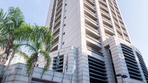 Um edifício alto com design moderno, apresentando uma entrada ampla e várias varandas.