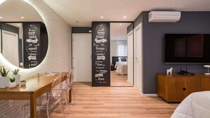 A modern bedroom with a TV, a wooden dresser, and a dining area with a table and chairs. - #TR403 | Cyclinn Faria Lima Itaim (Itaim Bibi)