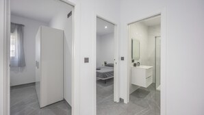 Une chambre d’hôtel moderne comprenant un lit, une salle de bain avec un miroir et un lavabo, et une armoire.