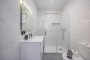 Une salle de bain moderne avec une douche à parois de verre, un lavabo blanc et des toilettes.