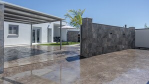 Une maison moderne dotée d’un patio, d’un espace salon extérieur abrité et d’un mur en pierre.