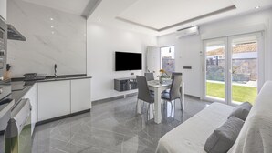 Une cuisine moderne avec un coin repas, un téléviseur à écran plat et une porte-fenêtre coulissante donnant sur l’extérieur.