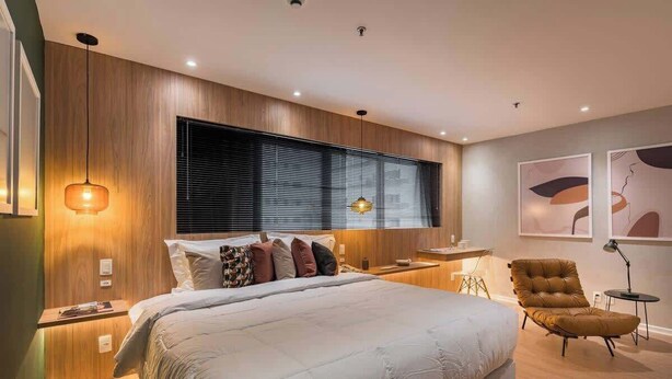 Une chambre à coucher moderne avec un grand lit, une tête de lit en bois, un bureau et une chaise.