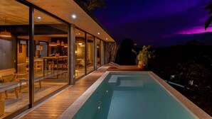 Una casa moderna amb piscina, portes de vidre i zona de menjador.