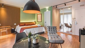 Une chambre d’hôtel moderne équipée d’un lit, d’un coin salon, d’une table à manger et d’une grande fenêtre.
