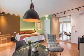 A modern hotel room with a bed, a seating area, a dining table, and a large window. - #RB406 | Cyclinn Cidade Jardim Itaim (Itaim Bibi)