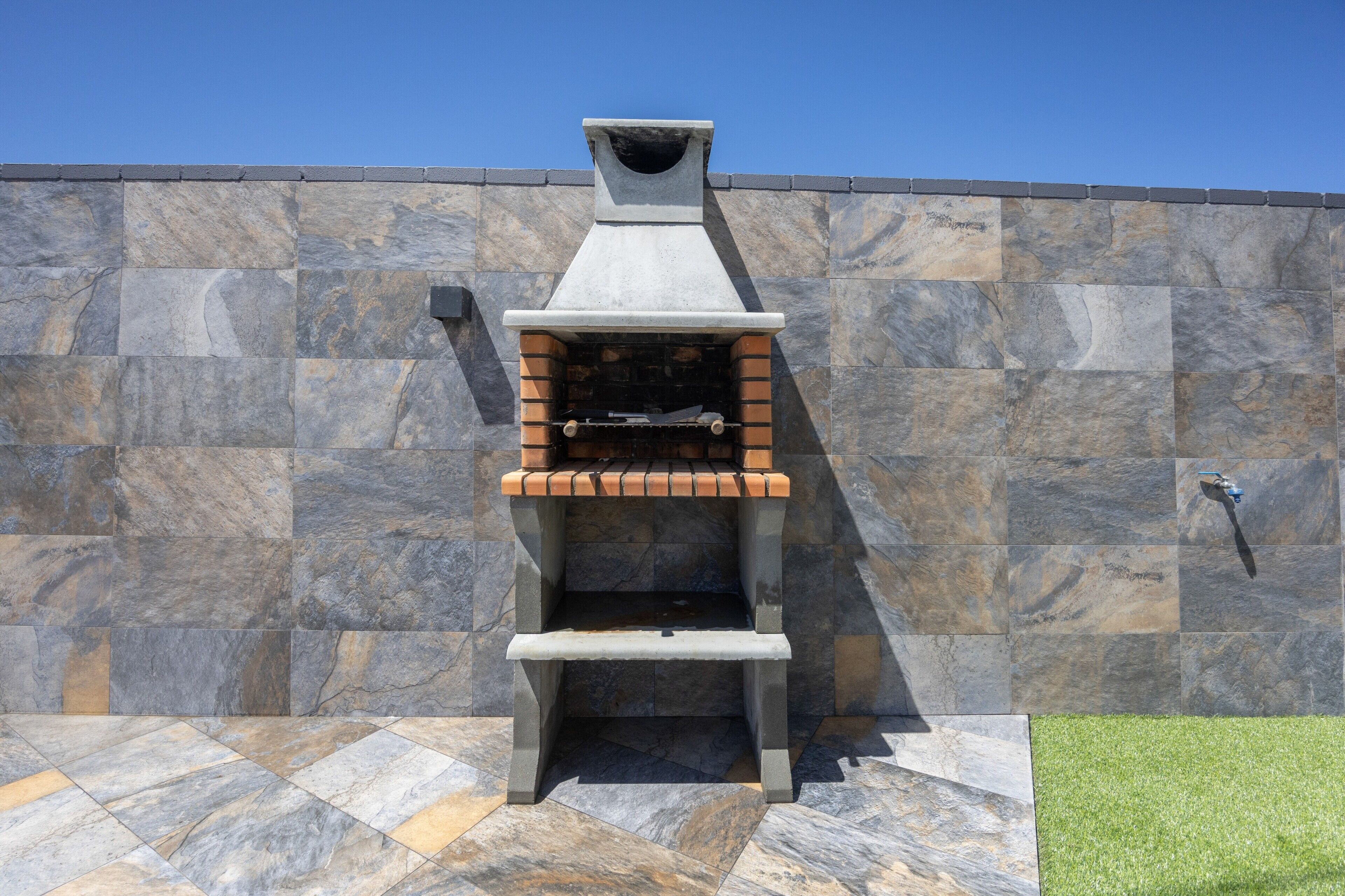 Eine Steinsäule mit integriertem Grill und Wasserhahn.