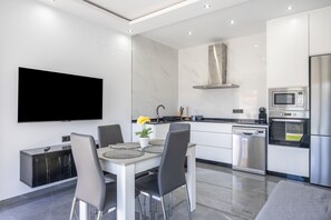 Eine moderne Küche mit Flachbildfernseher, einem Esstisch mit Stühlen und einer Couch.
