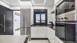 Eine moderne Küche mit Edelstahlgeräten, einer schwarzen Arbeitsplatte und einem Fenster mit Blick auf ein Gebäude.