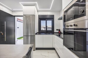 Eine moderne Küche mit Edelstahlgeräten, einer schwarzen Arbeitsplatte und einem Fenster mit Blick auf ein Gebäude.