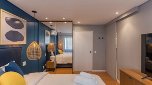 Quarto moderno com uma cama grande, mesas de cabeceira, guarda-roupa e espelho.