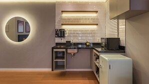 Uma cozinha compacta com pia embutida, micro-ondas e geladeira.