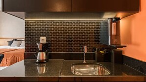 Eine moderne Küche mit Backsteinrückwand, einer Kaffeemaschine und einem Spülbecken.