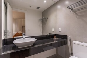 A modern bathroom with a large white sink, a black countertop, a glass shower enclosure, and a visible toilet. - #IN606 | Cyclinn Jesuíno Arruda Itaim (Itaim Bibi)