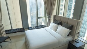Een moderne slaapkamer met een groot bed, een nachtkastje en uitzicht op hoge gebouwen door grote ramen.