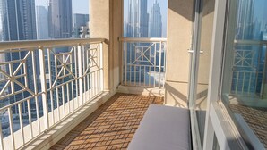 Een balkon met uitzicht op hoge gebouwen, een houten vloer en een witte balustrade.