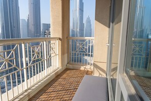 A balcony with a view of tall buildings, a wooden floor, and a white railing. - High Floor with Full Burj Khalifa and Fountain Views, Pool Table, Gym, Pool (Dubai)