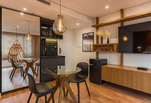 A modern kitchen with a glass dining table, black chairs, a wooden counter, and a black refrigerator. - #RD510 | Cyclinn Vila Olímpia (Vila Olímpia)