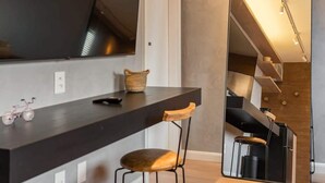 A modern kitchen with a dark countertop, a chair, a small table, and a mirror reflecting a staircase. - #BE1902 | Cyclinn Vila Olímpia Berrini (Berrini)