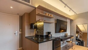 A modern kitchen with a black countertop, wooden cabinets, a built-in oven, and a coffee maker. - #BE1902 | Cyclinn Vila Olímpia Berrini (Berrini)